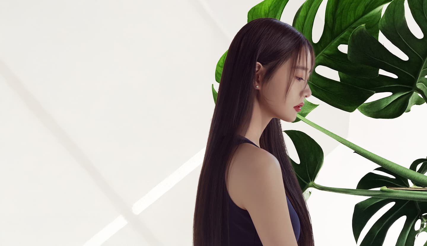몬스테라 잎 그림자가 드리운 벽 앞, 긴 생머리의 뒷모습